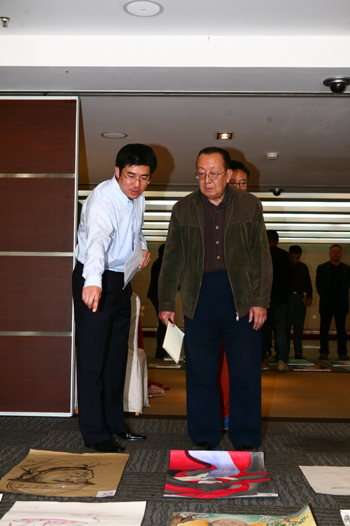 画家,中国美术家协会插图装帧艺术委员会副主任秦龙(右)正在评选作品